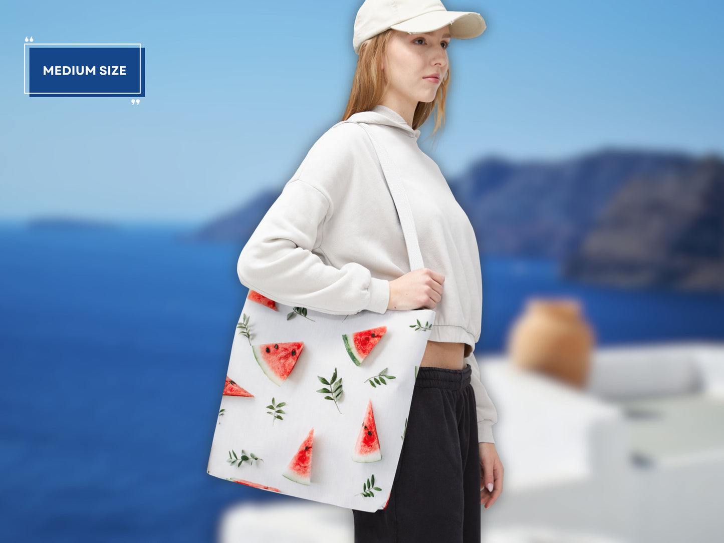 woman holding the medium watermelon bag, demonstrating its size and versatility. This image showcases how this watermelon tote bag is ideal for shopping trips or a day at the beach. The watermelon design adds a fun and summery touch, making it a perfect beach tote bag. This shoulder bag fruit option is both practical and stylish. The medium size makes it a great reusable shopping bag.