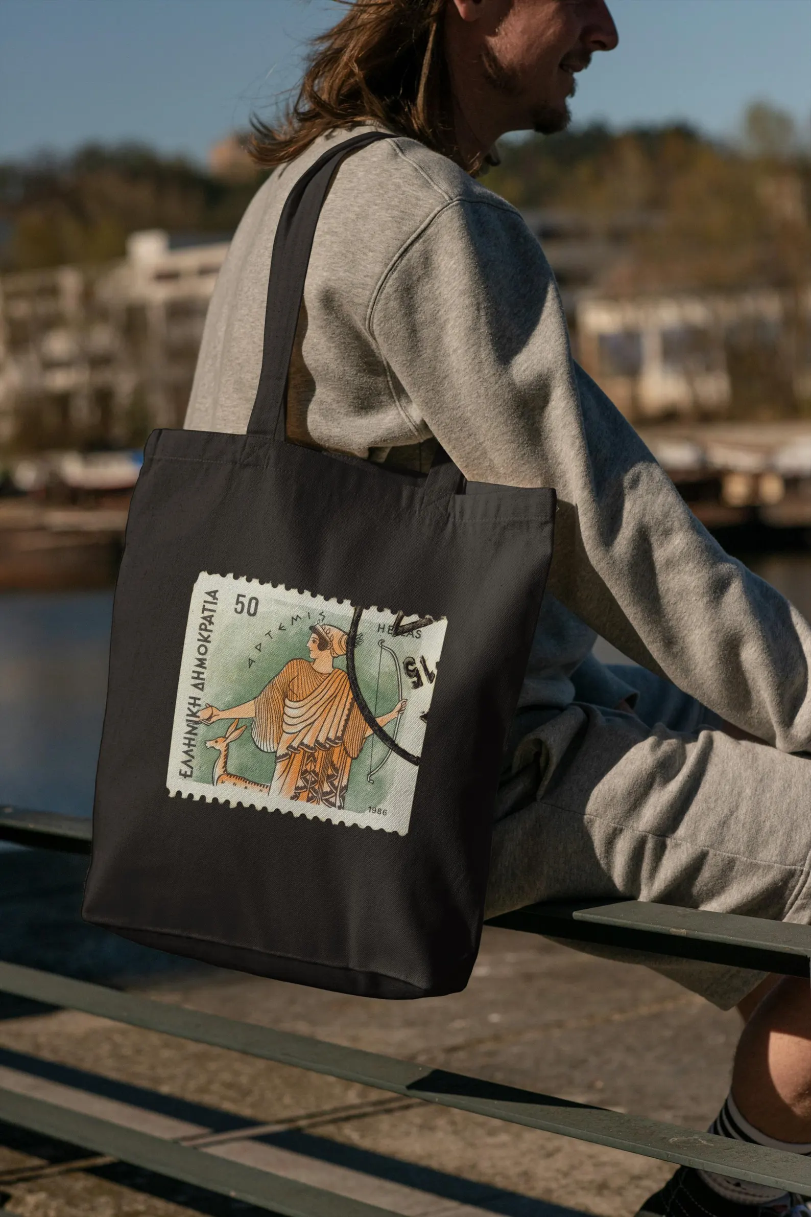 Man holding the Artemis art bag, emphasizing texture and print clarity. This greek mythology tote bag shows off its goddess artemis illustration in a striking way, great for gift history student ideas or as a greek art bag.
