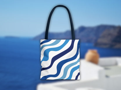 The blue bag in a Santorini setting. The image shows the stripes of the shoulder bag in different shades of blue and the blue color of the handles, an ideal bag for your summer vacation in Greece to complete your Santorini outfit