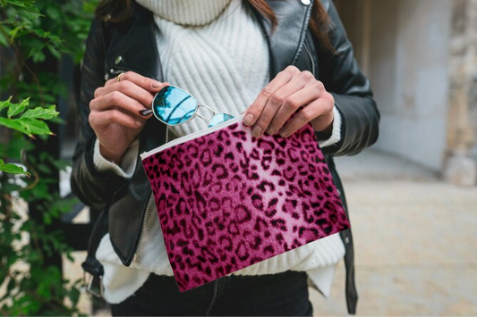 A woman elegantly holding the pink leopard clutch, showcasing its vibrant design and practical loop handle. This animal print bag is a chic animal handbag, perfect for adding a bold statement to any outfit. It is a versatile vegan leather clutch.