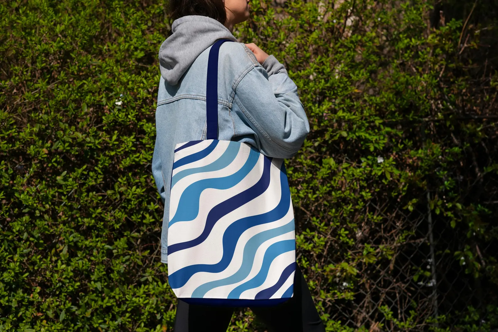 Blue Aesthetic Tote Bag in a casual, everyday setting, such as walking through a park or enjoying a coffee. This image emphasizes its style and functionality as an everyday blue bag. The blue and white design adds a touch of personality, making it a fashionable and practical choice for daily use. The image highlights the bag's comfortable straps and durable construction.