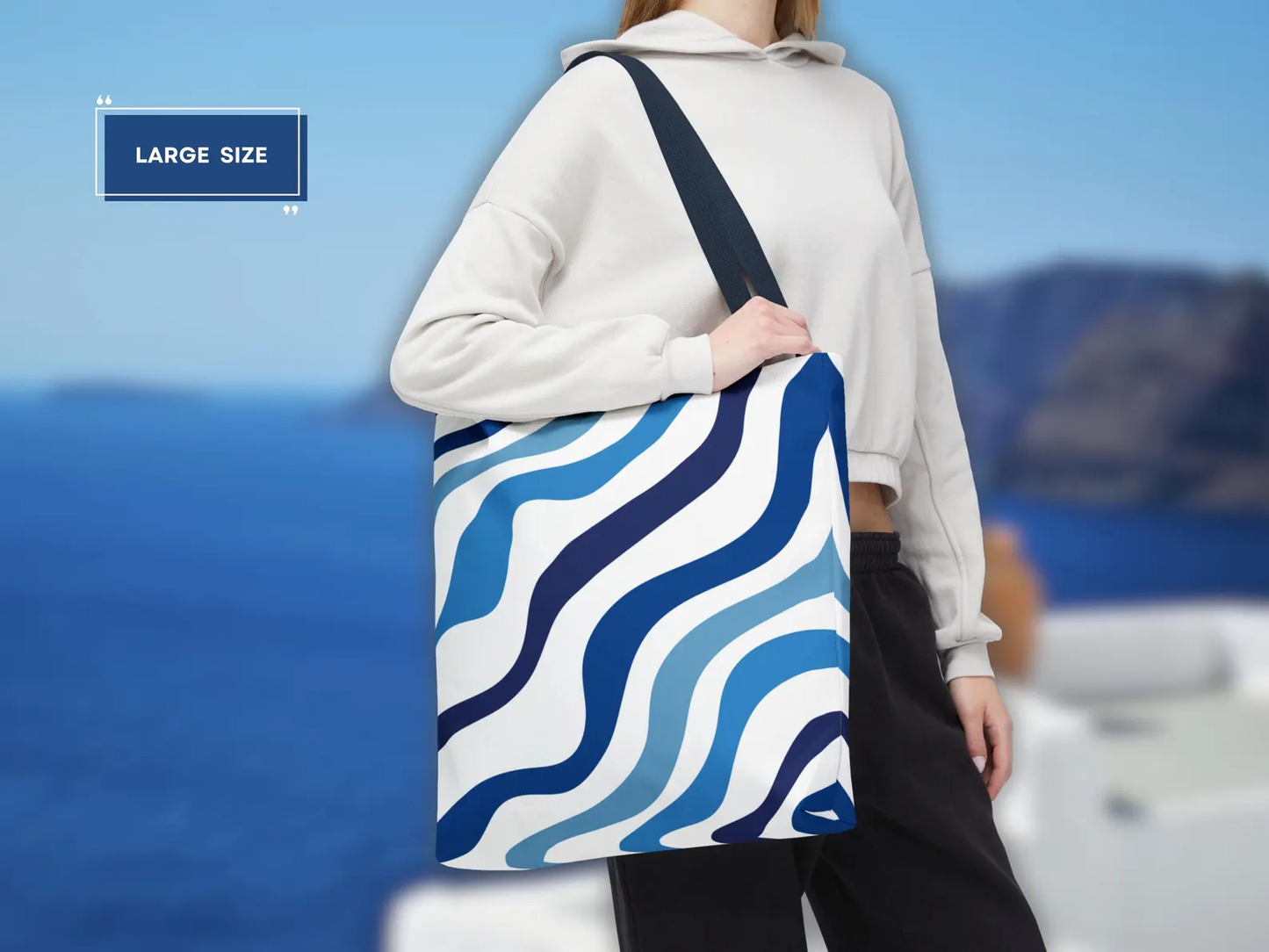 A person carrying the large size of the Blue Aesthetic Tote Bag in a vibrant city setting, showcasing its stylish appeal and versatility. This image highlights how the bag complements an urban outfit, making it a chic accessory for a day out. The elegant blue and white design adds a touch of Mediterranean flair, perfect for those who appreciate a stylish blue tote.