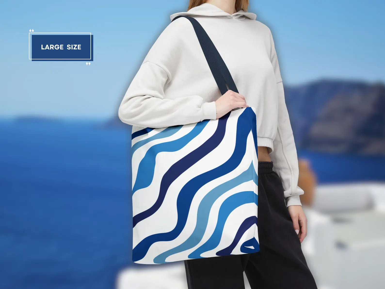 A person carrying the large size of the Blue Aesthetic Tote Bag in a vibrant city setting, showcasing its stylish appeal and versatility. This image highlights how the bag complements an urban outfit, making it a chic accessory for a day out. The elegant blue and white design adds a touch of Mediterranean flair, perfect for those who appreciate a stylish blue tote.