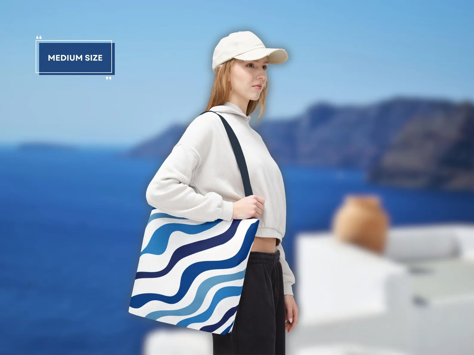 Small Blue Aesthetic Tote Bag on a sandy beach, filled with beach essentials like a towel, sunscreen, and a book. This image captures the essence of a perfect beach day, highlighting the bag's practicality and style. The blue and white design complements the sunny atmosphere, making it an ideal blue beach bag. This image conveys the bag's spaciousness and durability, making it a must-have for any beach lover.